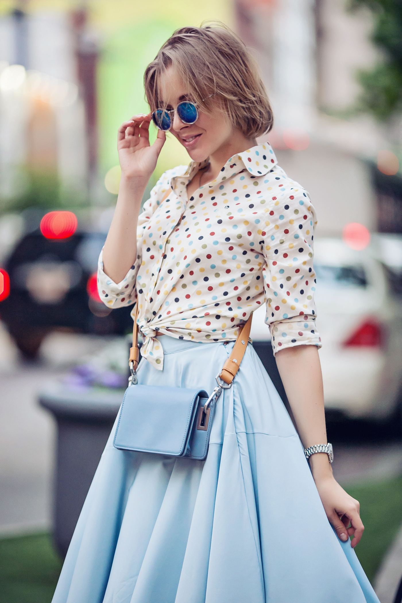 darya kamalova a fashion blogger from thecablook in dallas texas on the bycicle in polka dot shirt and blue skirt with gold espadrilles and other storie bag for rewardstyle rsthecon-22 copy